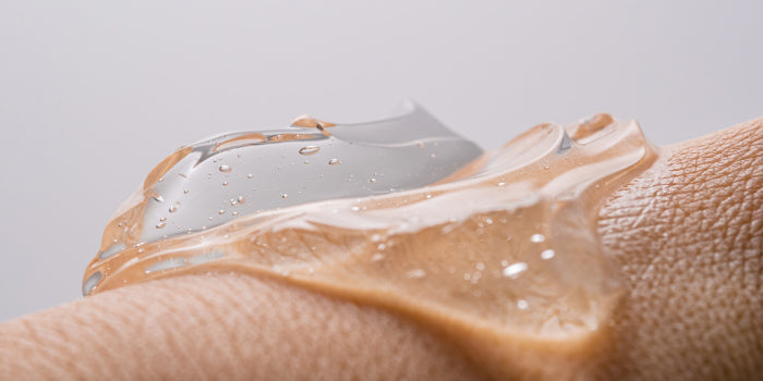 Close-up of a man’s hand applying clear anal lubricant from a bottle, symbolizing comfort and safe male intimacy.