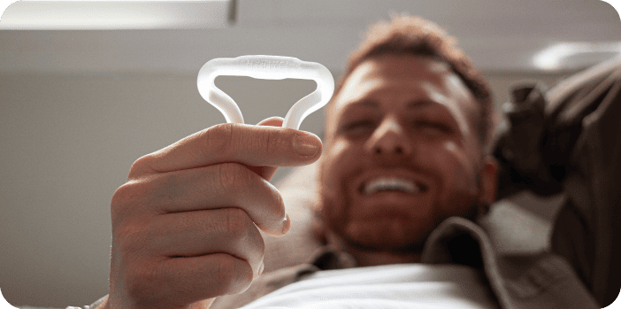 Man smiling holding products and devices for male health and wellness.