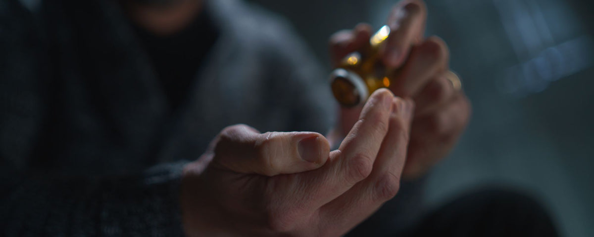 A man is taking some pills from a bottle
