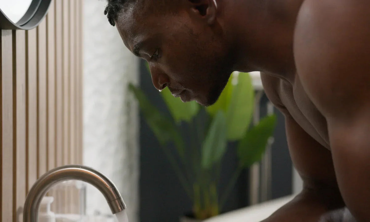 A black man washing his face with water