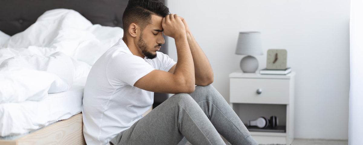 a man worried about his sexual health sit next to a bed