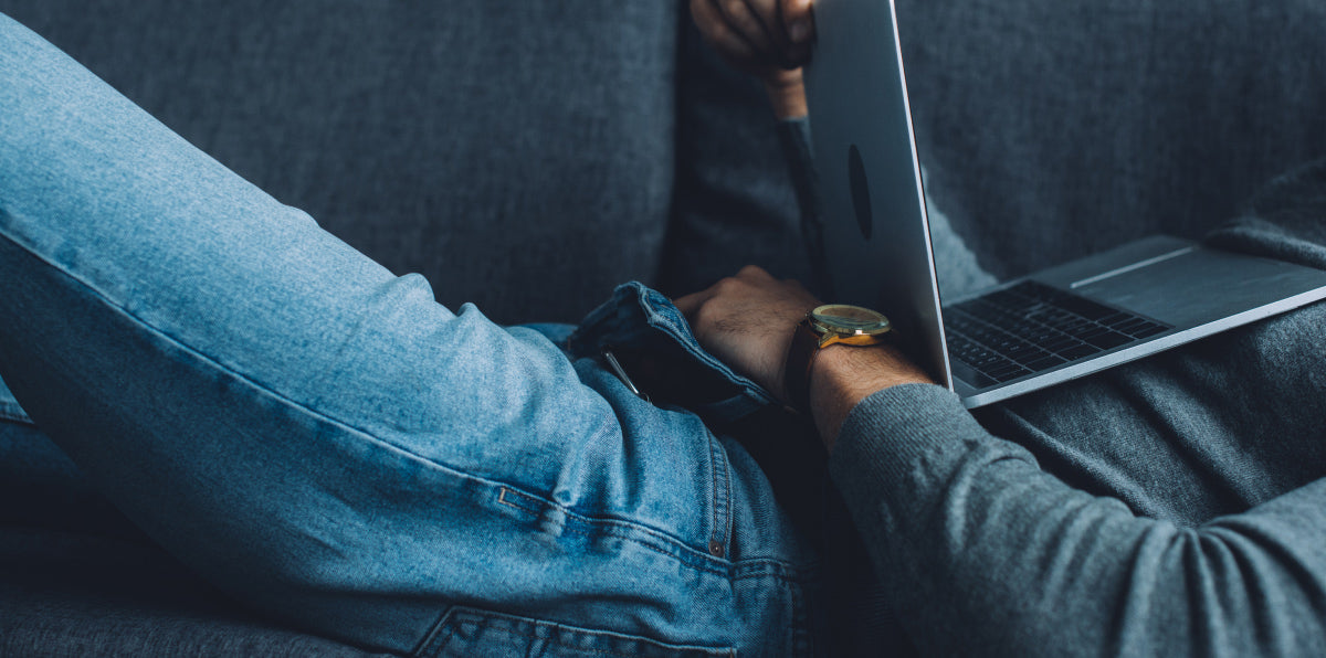 a man stimuling himself on the couch while watching something in a laptop