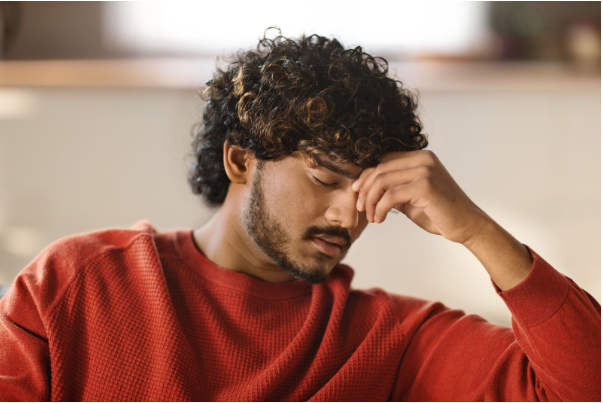 Man holding his face in sadness, representing the challenges men face when talking about mental health.