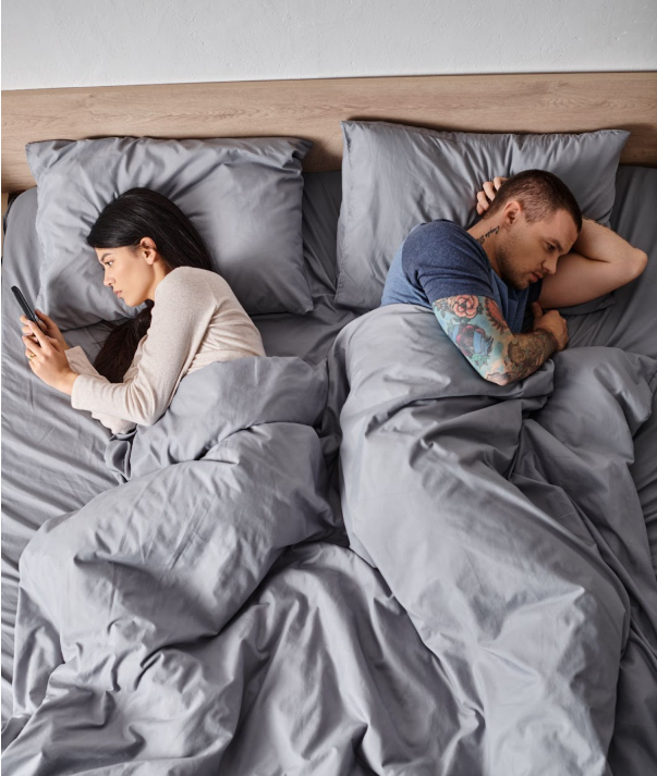 Couple sitting in silence on a couch, symbolizing emotional distance in a sexless marriage.