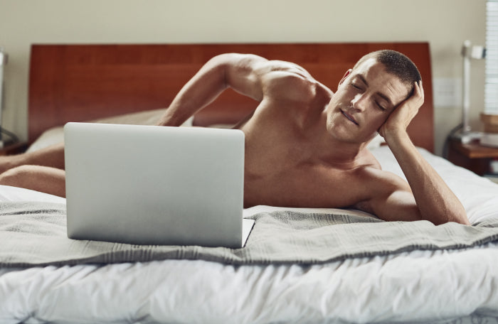 Man with laptop simulating masturbation, exploring masculinity and the impact of porn on male perception in modern society.